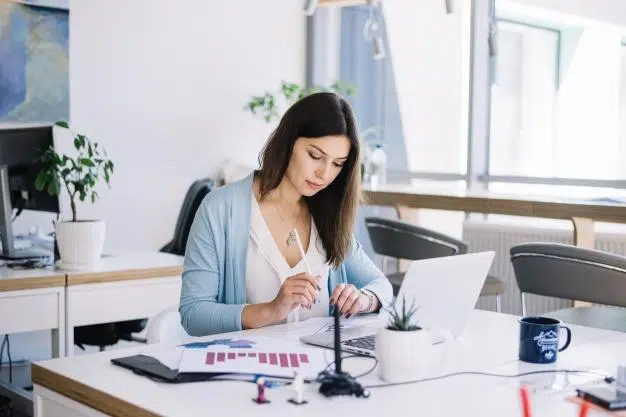 Woman at desk with laptop and printouts