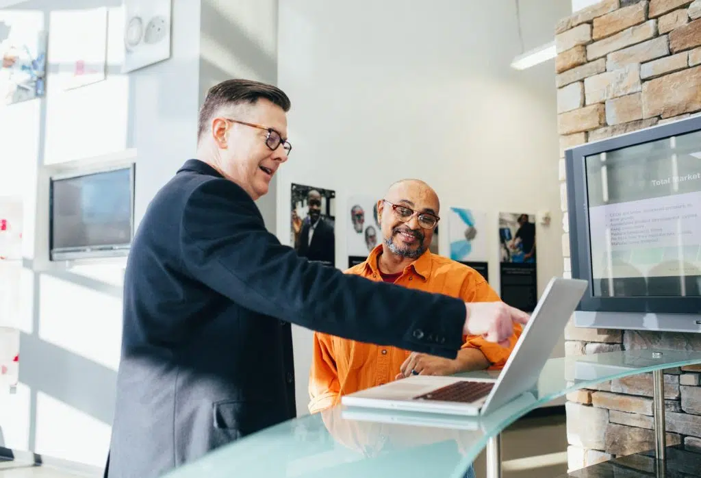 Two men at a laptop smiling