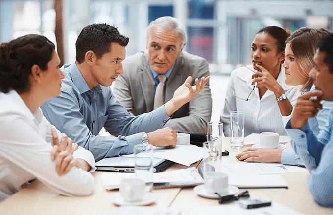 people in a meeting sat at a table talking