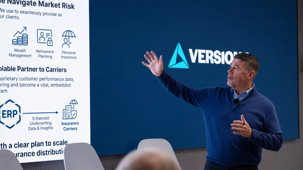 Man presenting in a modern conference room, gesturing toward a large screen displaying financial services icons and text, with a corporate logo on a blue background behind him