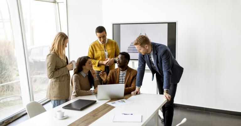 Group of colleagues gathered around a laptop talking
