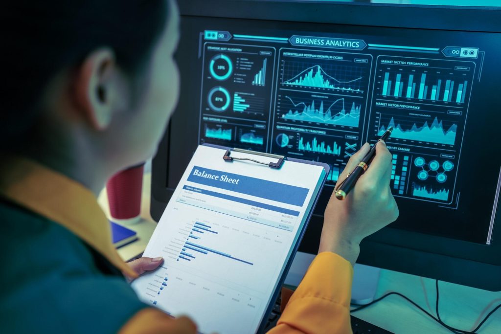 An Asian businesswoman analyzes digital charts on a computer screen, reviewing performance reports