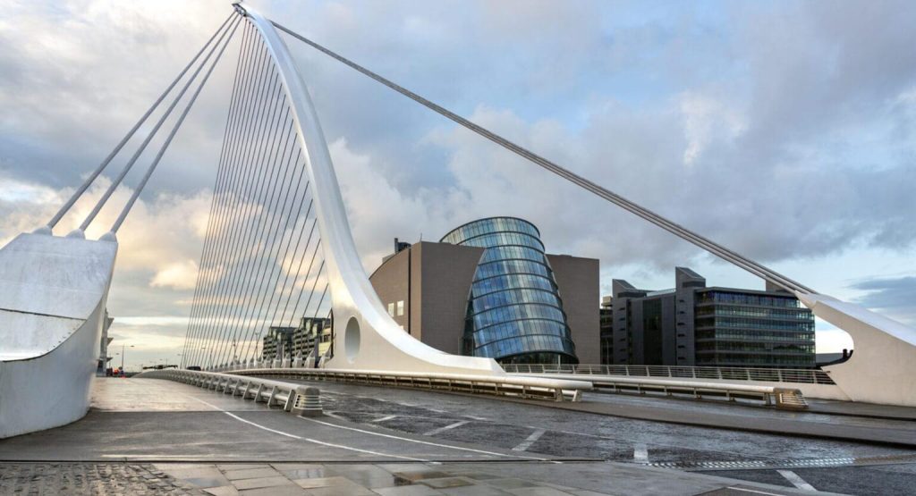 The Samuel Beckett Bridge and the building on the waterfront near the Convention Center - Dublin city center in the Republic of Ireland. This is a cable-stayed bridge that joins Sir John Rogerson's Quay on the south side of the River Liffey to Guild Street and North Wall Quay in the Docklands area. The innovative architect Santiago Calatrava designed this and a number of other bridges and buildings in Ireland.