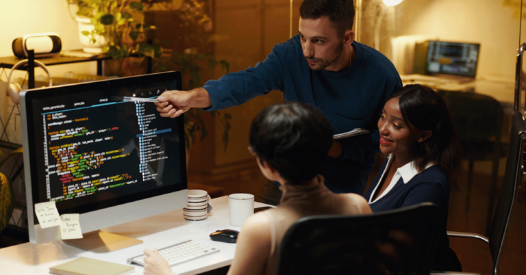 Man presenting to colleague in office meeting, pointing at screen during discussion.