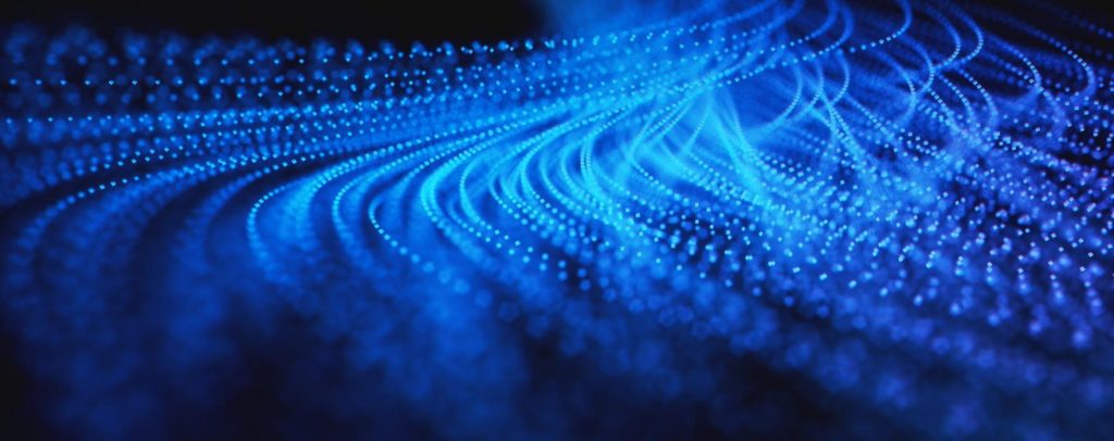 Abstract digital background of glowing blue particles arranged in flowing, wave-like patterns, resembling data streams or neural networks against a dark backdrop.